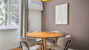 A dining area with a round wooden table and four grey upholstered chairs. An air conditioning unit is mounted on the wall above the table. - Blueground | Wieden, washer/dryer, nr Karlskirche (Vienna)