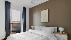 Una camera da letto con un letto grande, due comodini con lampade, una vista dalla finestra e un quadro astratto appeso al muro.