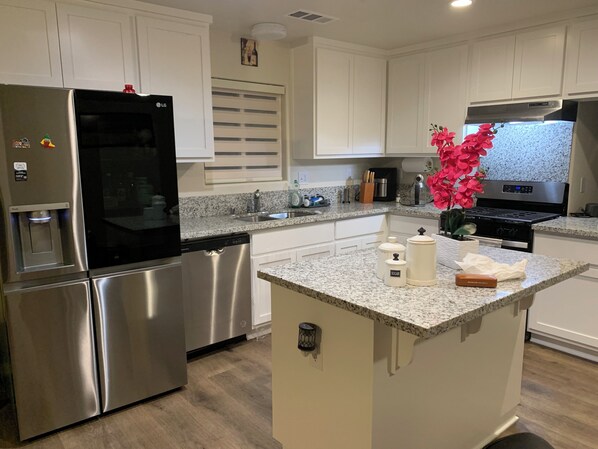 Una cocina moderna con electrodomésticos de acero inoxidable, encimera de granito y armarios blancos.