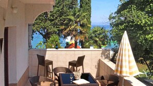 Eine Terrasse mit Korbmöbeln, einem Tisch und einem Sonnenschirm.