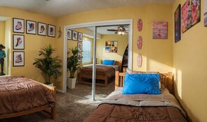 Ein Schlafzimmer mit zwei Betten, einer Schiebetür zum Balkon und verschiedenen Wandbildern.