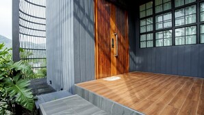 A modern building with a wooden door, a balcony with stone steps, and a view of greenery. - Harley 1 BDR Condo Kata Hill, 3 Mins To kata Beach (Karon)
