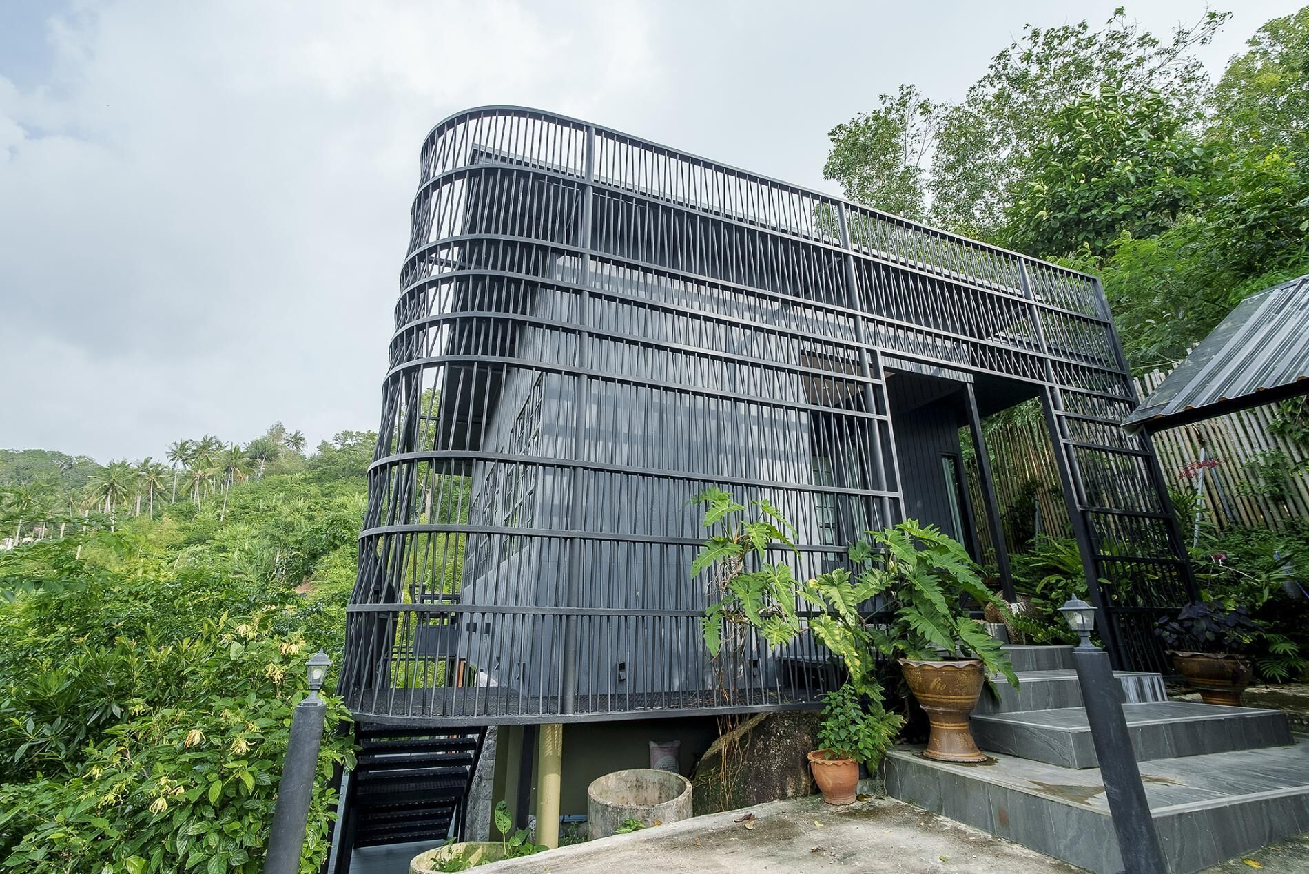 A modern building with a curved facade, surrounded by lush greenery.