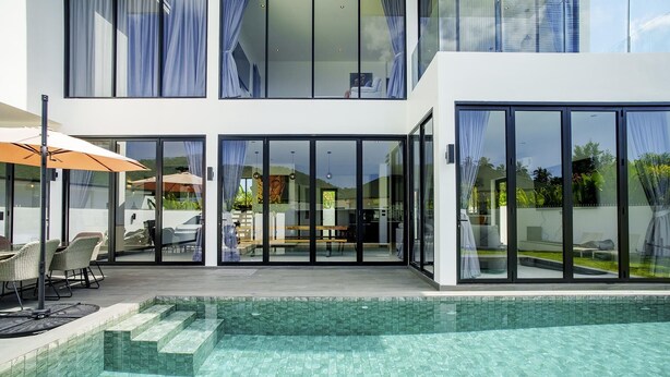 A modern house with a swimming pool, large glass doors, and outdoor furniture. - Camellia Pool Villa,Near Nai Harn And Rawai Beach (Tambon Rawai)