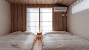 Una stanza moderna e accogliente con due letti, soffitto in legno e un'ampia finestra con vista.