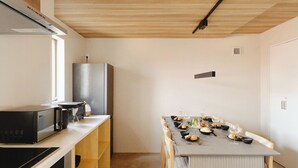 Una cucina moderna con zona pranzo, caratterizzata da mobili in legno, forno integrato e tavolo imbandito per sei persone.