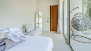 Une chambre à coucher moderne, dotée d’un grand lit, d’une lampe décorative suspendue et offrant une vue sur l’extérieur grâce à une porte vitrée.