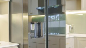Une cuisine moderne dotée d’un réfrigérateur en acier inoxydable, de meubles blancs et d’un distributeur d’eau intégré.