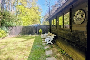 Ein Holzhaus mit einer Bank vor der Tür, einem Holzzaun und einem Garten.