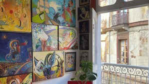 A room with a round table, a potted plant, and a balcony with a metal railing. -  Hostal Valpito Cultura y Arte (Valparaíso)