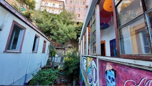 A narrow alleyway with buildings on either side, some with visible windows and doors, and a mural on one building. -  Hostal Valpito Cultura y Arte (Valparaíso)