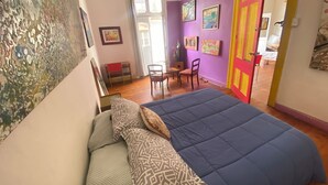 A bedroom with a bed, a chair, a desk, and a door leading to another room. -  Hostal Valpito Cultura y Arte (Valparaíso)