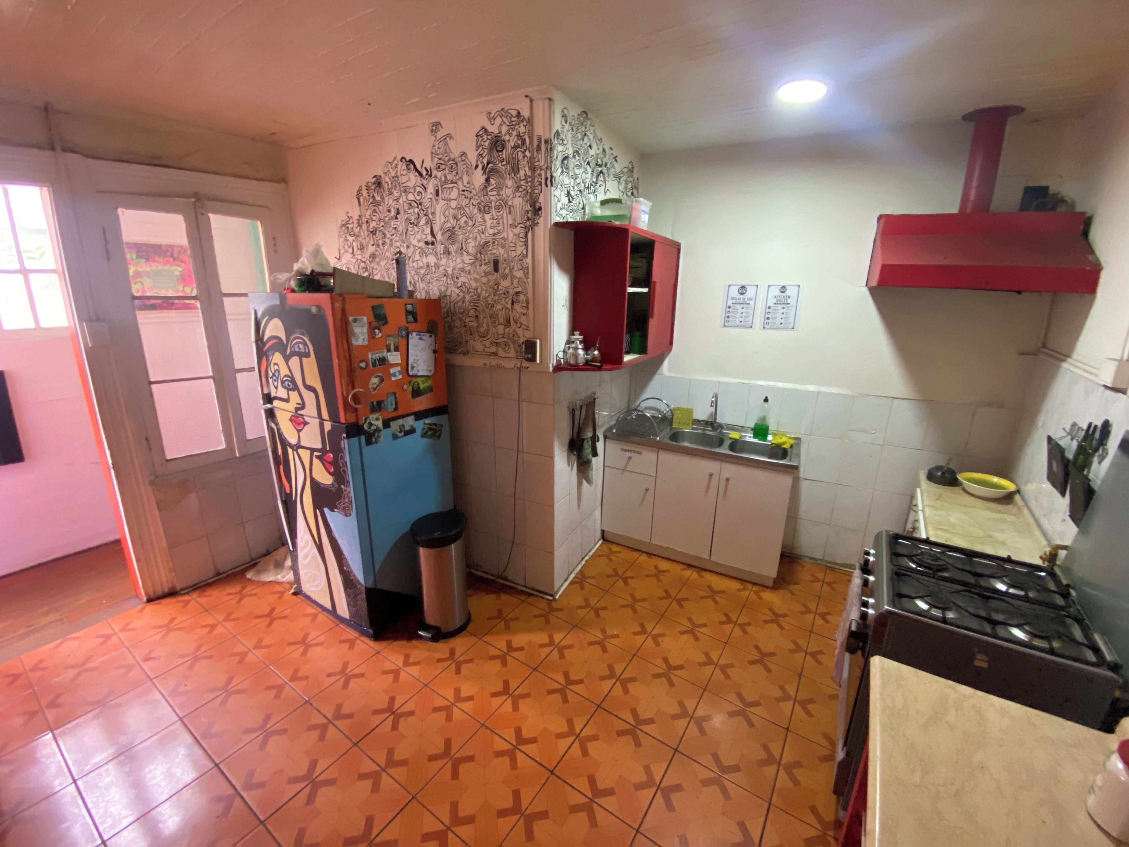 A kitchen with a refrigerator, sink, cabinets, and a stove.