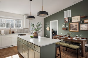 Een moderne keuken met een groot eiland, witte kastjes en een eetgedeelte met een houten tafel en stoelen.