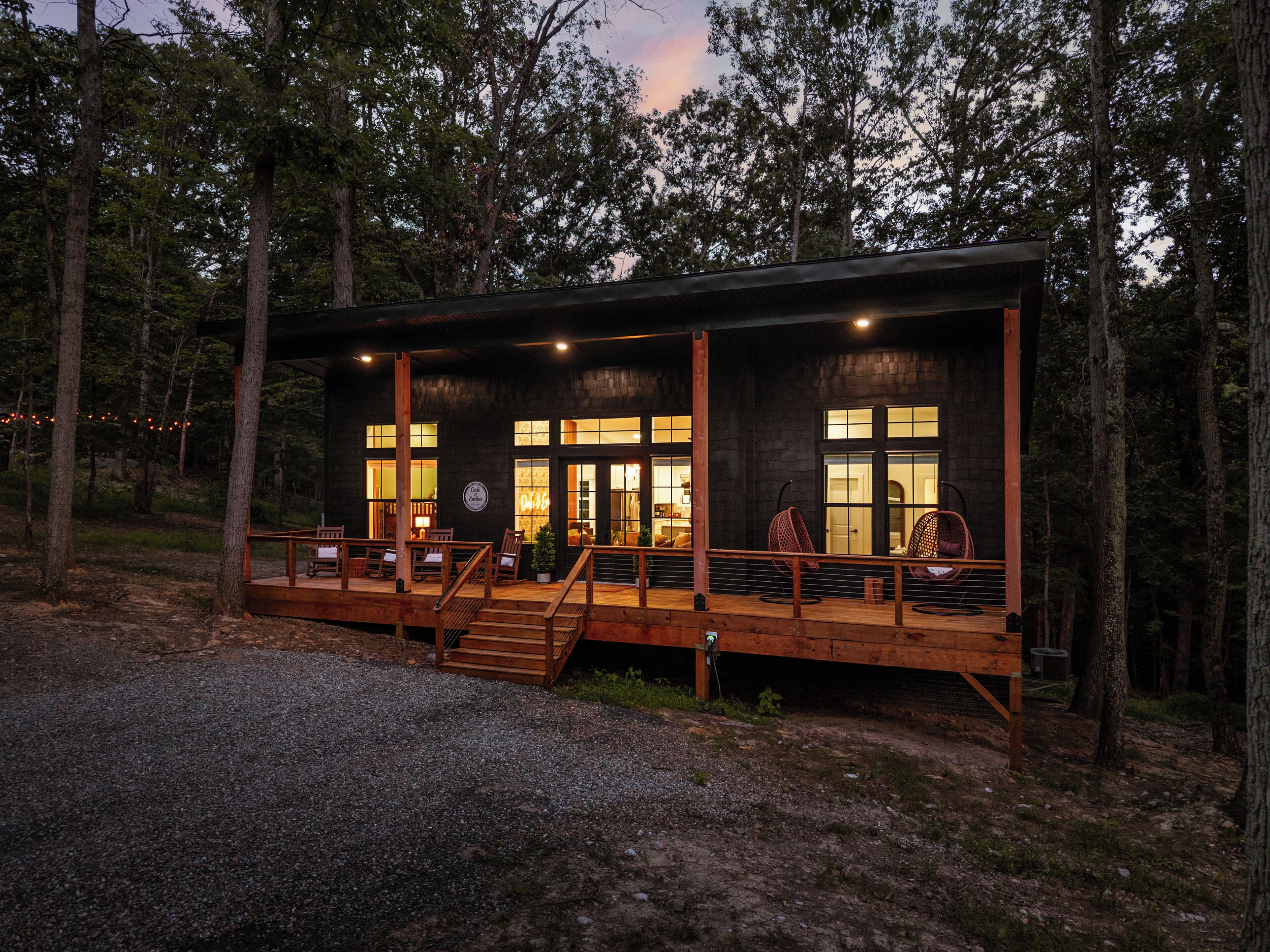 Eine Holzhütte mit einer Holzterrasse, mehreren Sitzbereichen und großen Fenstern.