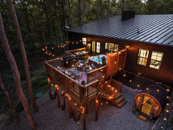 Una cabaña de madera con terraza, mobiliario exterior y jacuzzi.