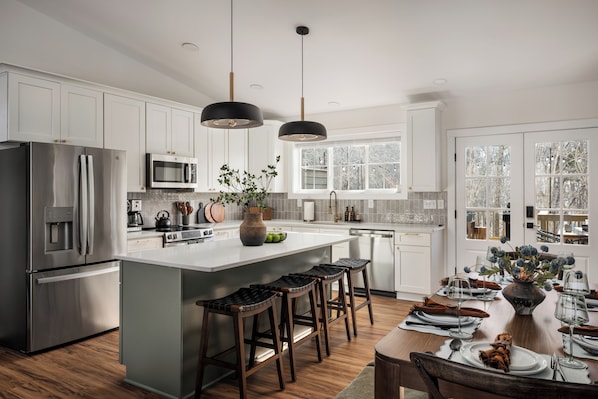 A modern kitchen with white cabinets, stainless steel appliances, and a large island with bar stools.