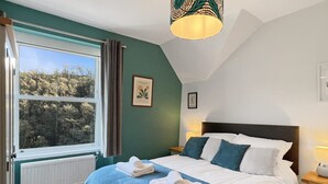 A bedroom with a bed, a window, a radiator, and a ceiling light fixture. - Ashridge, near Lynton (Lynton)