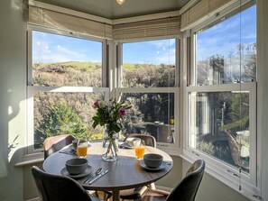 A dining area with a round table, chairs, and a view of a landscape through large windows. - Ashridge, near Lynton (Lynton)
