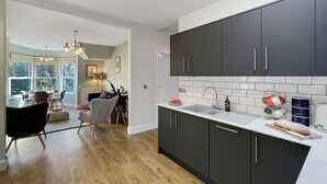 A modern kitchen with dark cabinets, a white countertop, and a large window. - Ashridge, near Lynton (Lynton)