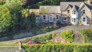 A hillside residential area with stone houses, a red car parked in front, and a clear sky. - Ashridge, near Lynton (Lynton)