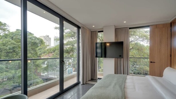 A modern hotel room with a large bed, a flat-screen TV, and a balcony with a city view. - Deluxe Nomad Pad In Granada | Walk Anywhere | 302 (Cali)