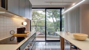 A modern kitchen with a large window, a coffee machine, and a wooden bowl on the counter. - Deluxe Nomad Pad In Granada | Walk Anywhere | 302 (Cali)