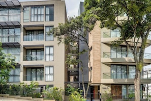 Un edificio moderno de varios pisos con balcones, ventanas grandes y una entrada visible que dice "Hyga".