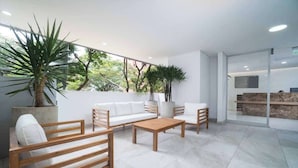 Un vestíbulo moderno y luminoso con zona de estar, ventanas amplias y plantas de interior.