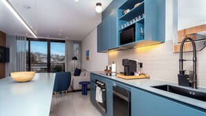 A modern kitchen with blue cabinets, a black faucet, and a built-in oven. - Deluxe 2-Bed • By Cali's Best Restaurants | 301 (Cali)