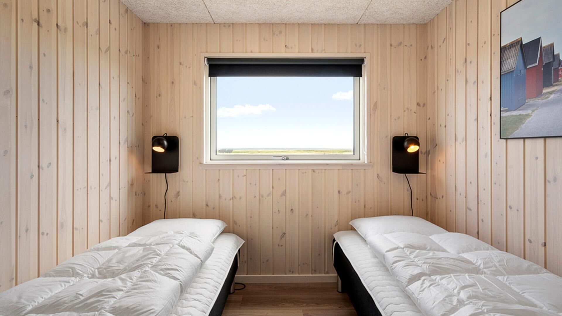 A room with two single beds, a window with a view, and two wall-mounted speakers.