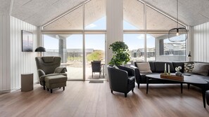 A spacious living room with a high ceiling, large windows, and a view of the outside. - VillaVilla 943 - Hvide Sande, Vestjylland (Hvide Sande)