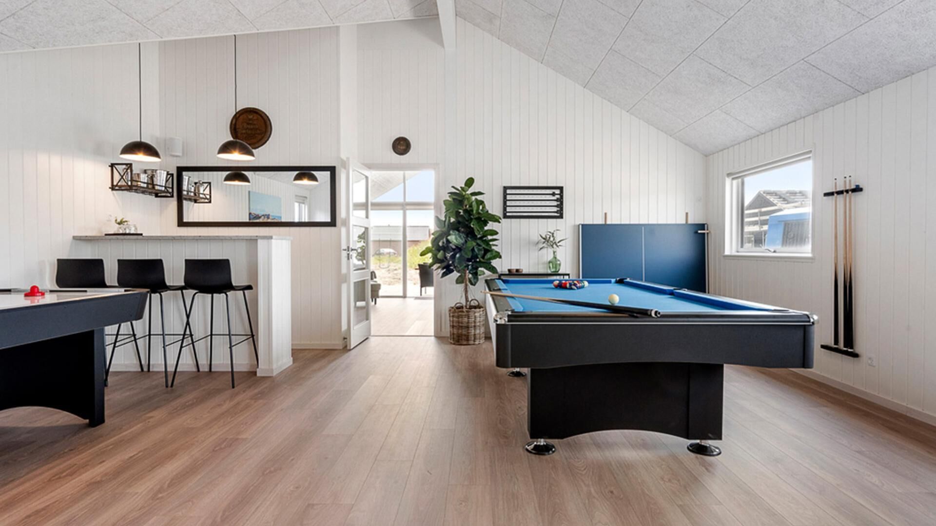 Een moderne leefruimte met een pooltafel, een bar en een eethoek.