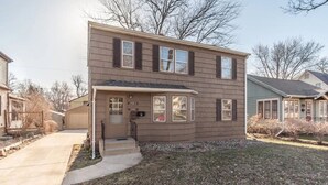 A two-story house with a front porch, a garage, and a small front yard. - Perfect 2-bedroom apartment near McKennan Park and Downtown! (Sioux Falls)