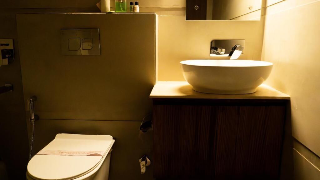 A compact bathroom with a toilet, a sink with a vessel basin, and a cabinet.