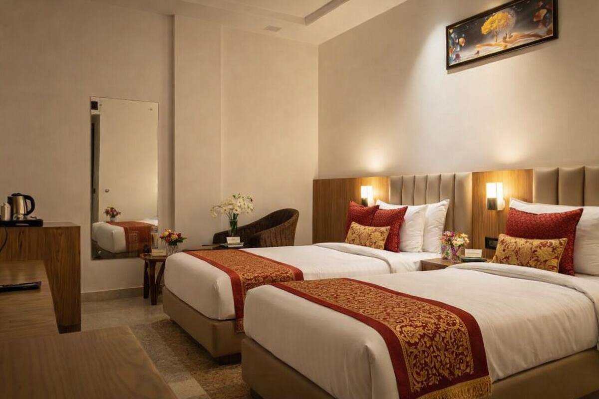A hotel room with two beds, a desk, a chair, and a painting on the wall.