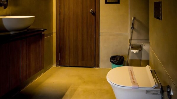 Une petite salle de bain avec une porte en bois, un lavabo blanc et des toilettes avec un abattant.