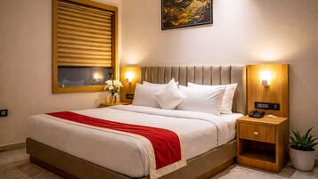 Una habitación de hotel con una cama, mesitas de noche, una lámpara de noche, una obra de arte en la pared, una ventana con persianas y una planta en maceta.