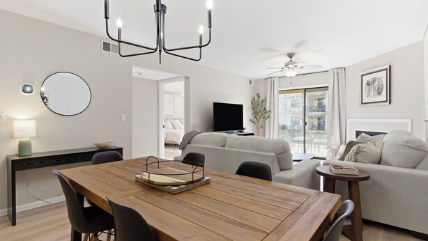A modern living room with a wooden dining table, a grey sofa, and a TV. - Walk in NO STAIRS 2 Bedroom Condo in Pointe Royale Golf Village NEW FOR 2026 (Branson)