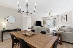 Ein modernes Wohnzimmer mit einem Holzesstisch, einem grauen Sofa und einem Fernseher.