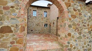 A stone building with a courtyard, featuring a brick pathway and arched entrance. - 2 bedroom awesome apartment in Trequanda (Trequanda)