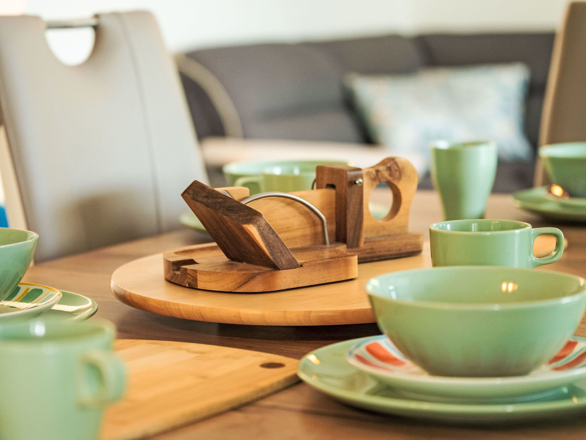 Una bandeja de madera con un portavasos, una taza verde y un plato sobre una mesa.