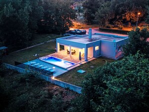 Ein modernes Haus mit Swimmingpool, Sitzgelegenheiten im Freien und einer überdachten Terrasse.
