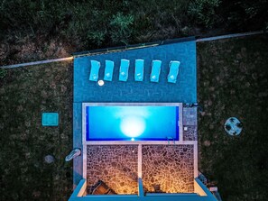 Un espace piscine aménagé sur le toit, avec un mur en pierre et une piscine bleue.