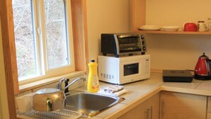 Una cocina compacta con un lavamanos, microondas, tostadora y tetera.