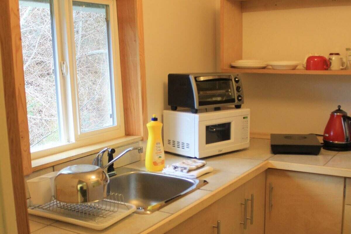 A compact kitchen with a sink, a microwave, a toaster, and a kettle.