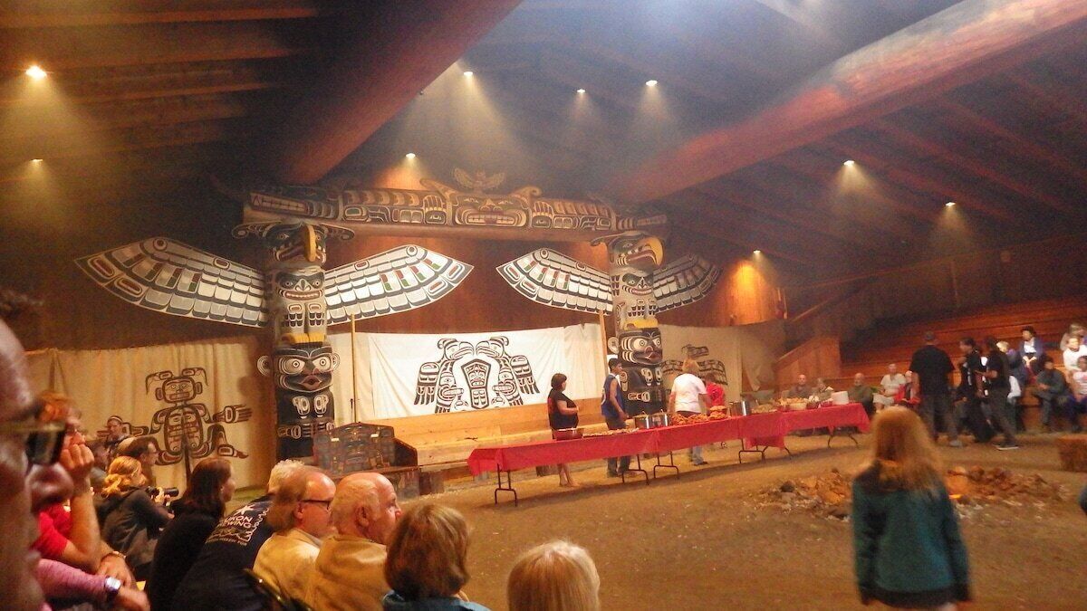 An indoor event with a stage, audience, and totem poles.