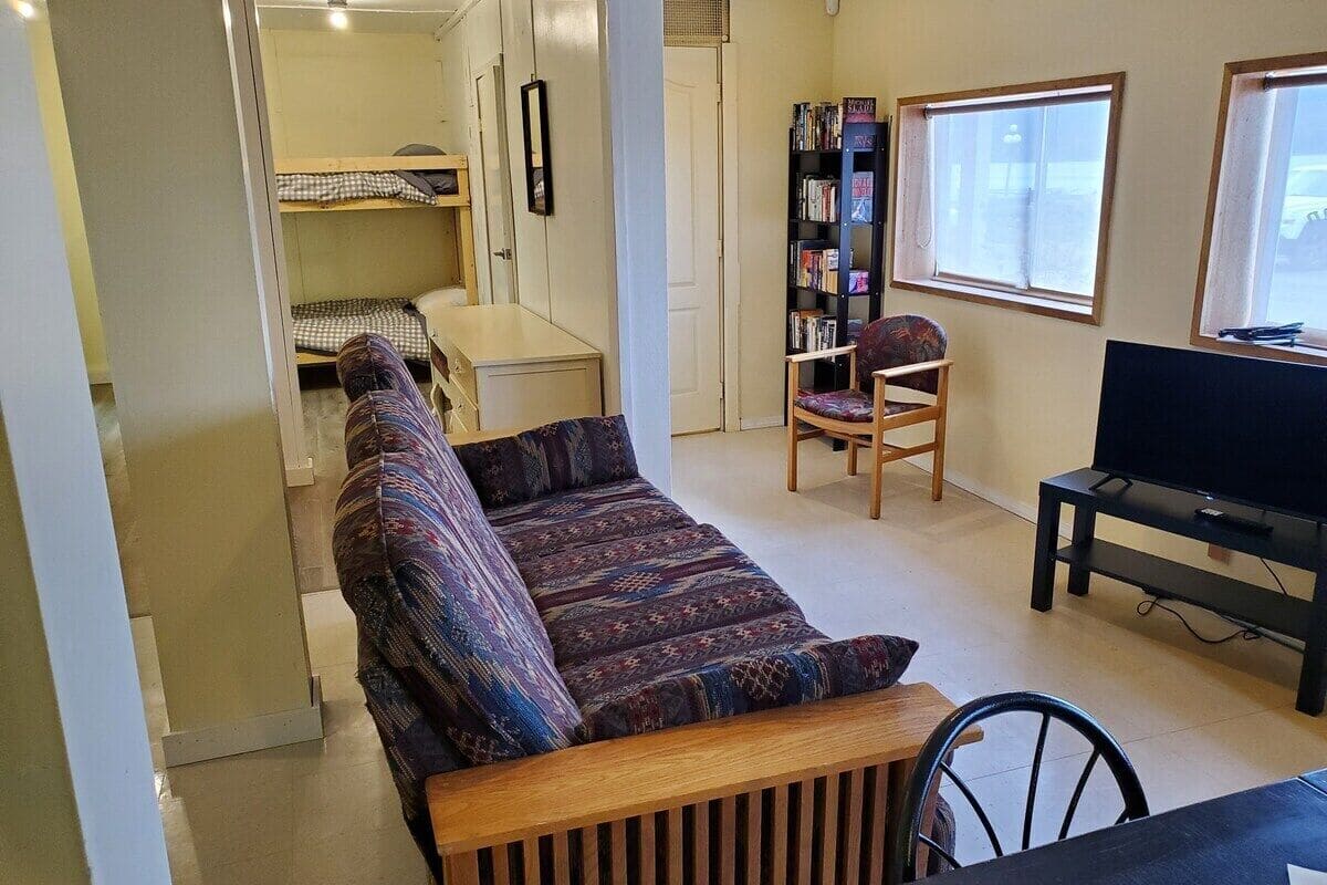 A compact living space with a sofa, a dining table, a TV, and a bookshelf.