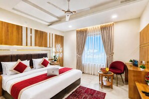 A hotel room with a bed, a desk, a chair, a ceiling fan, and a window with curtains. - Hotel All Time Residency New Delhi (New Delhi)