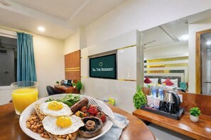 A breakfast setup with eggs, beans, mushrooms, and tomatoes on toast, a glass of orange juice, and a TV displaying 'ALL TIME RESIDENCY' in a hotel room. - Hotel All Time Residency New Delhi (New Delhi)